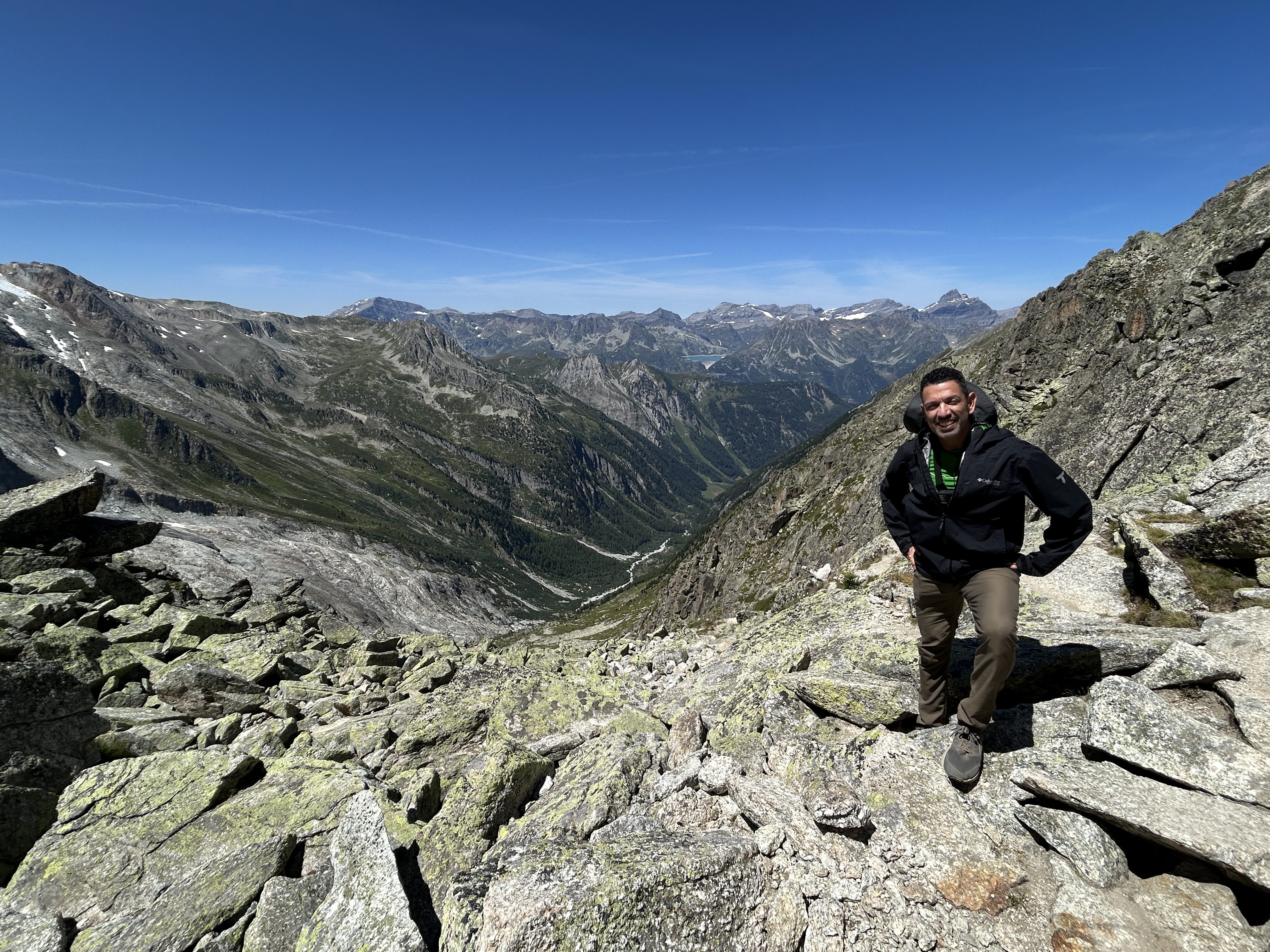 Richard Flores at the top of Fenêtre d'Arpette on the Walker's Haute Route, smiling, dramatic valley and mountains behind him