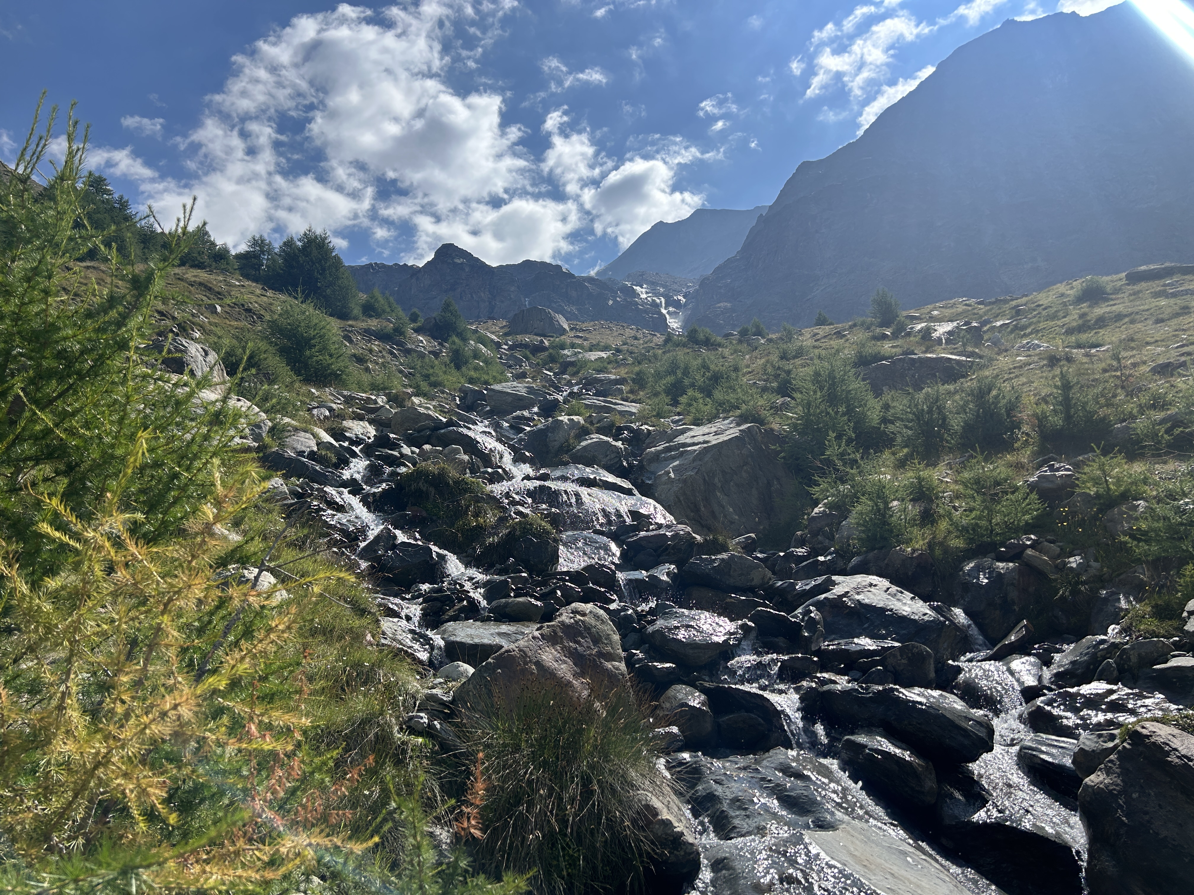 Rocky mountain stream cascading through boulders with glacier and peaks in the background, Walker's Haute Route