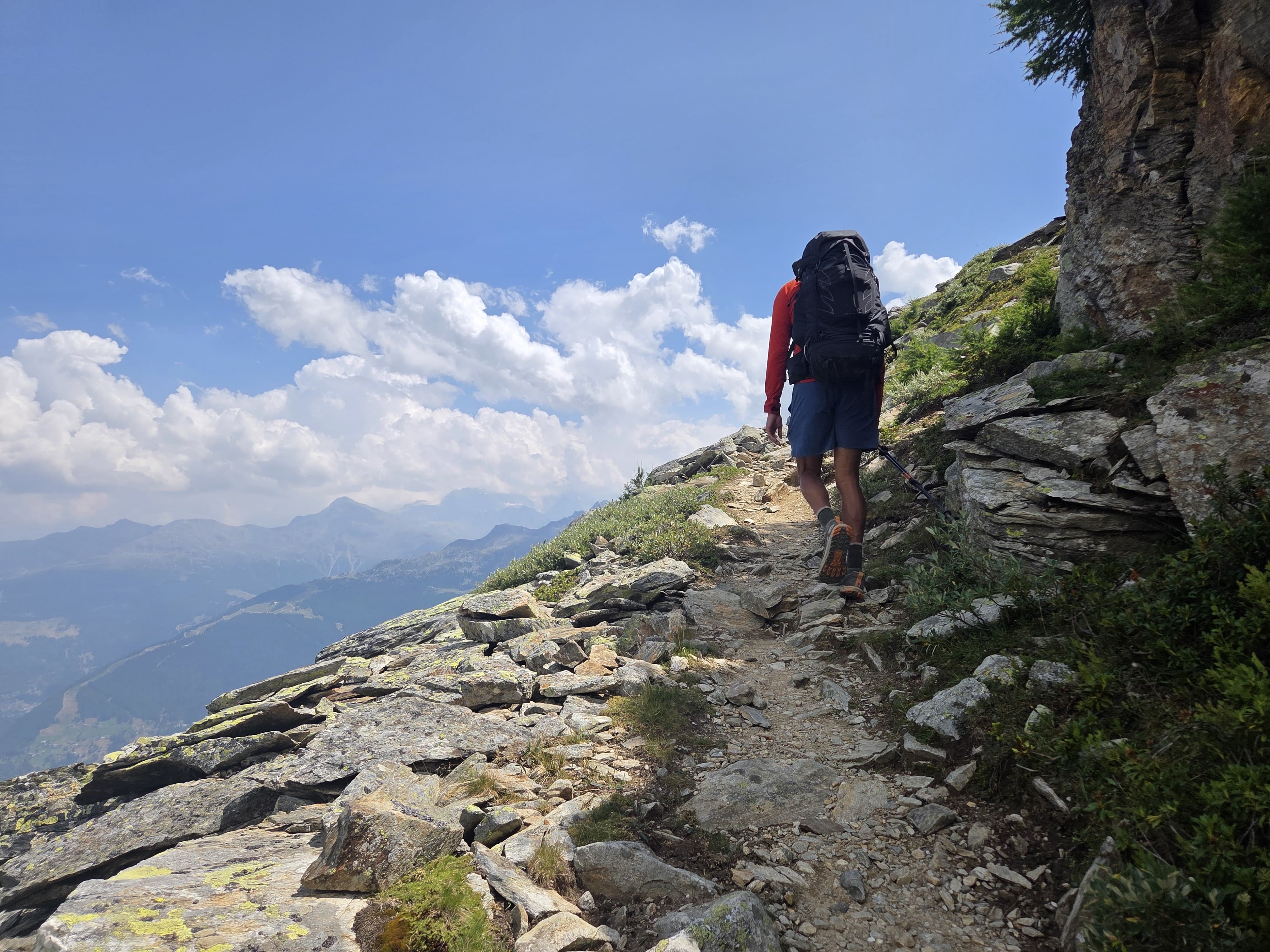 Richard Flores hiking up a rocky ridge on the Walker's Haute Route, seen from behind, full pack, blue sky